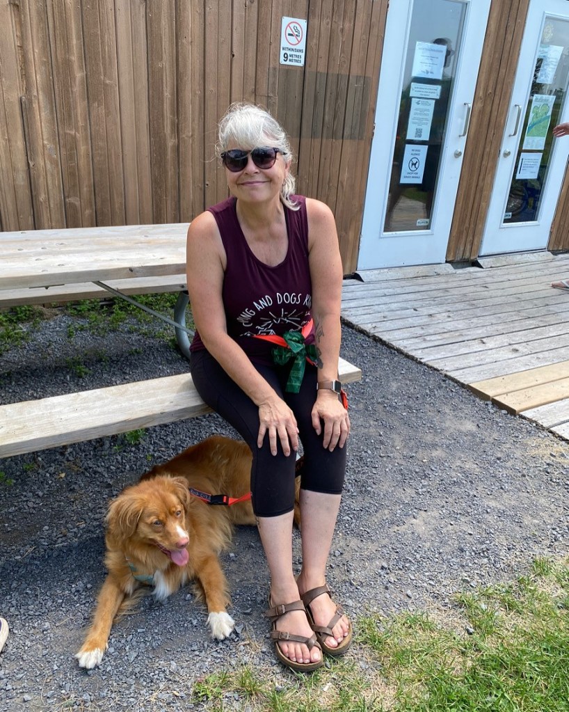 Picture of me sitting on a picnic table with Roxy laying behind my legs